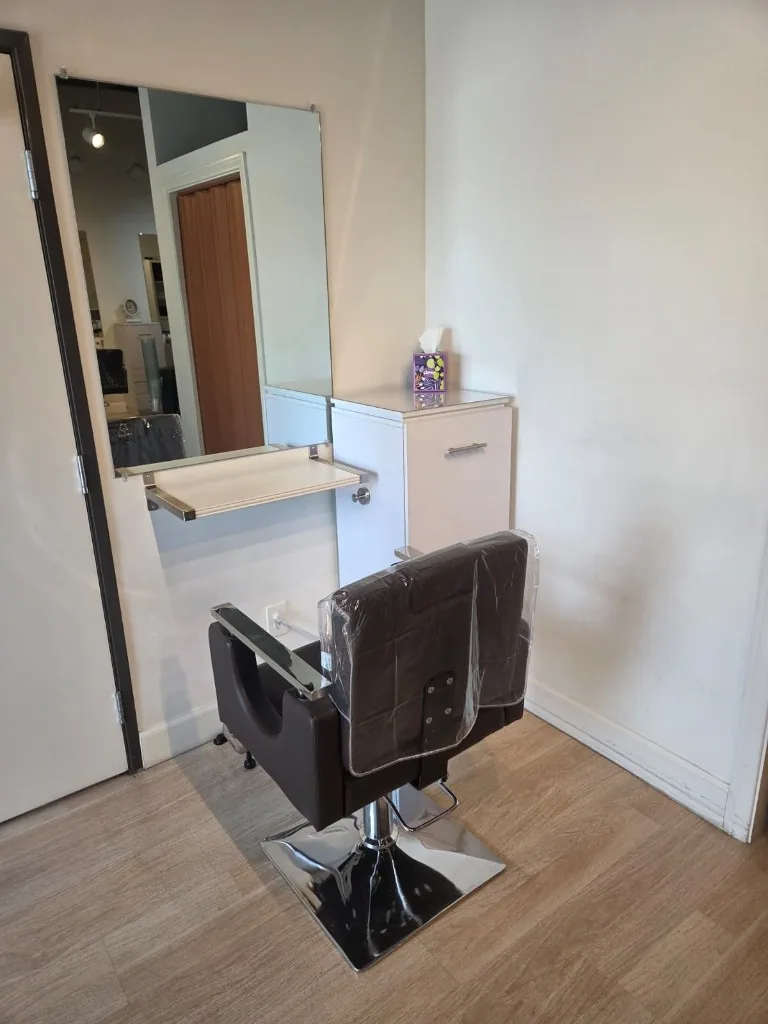 A styling station with chair, mirror, and cabinet at Glow Salon & Spa
