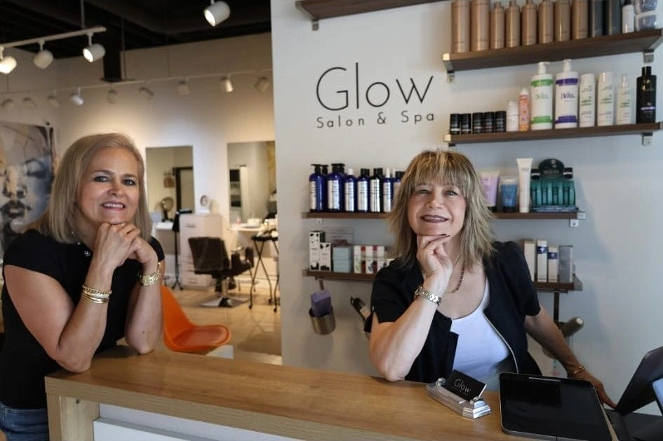 Linet and Carineh, co-owners of Glow Salon & Spa, smiling at the reception desk in Granada Hills